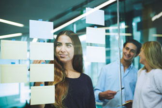 Campus group sticking postit notes on glass wall