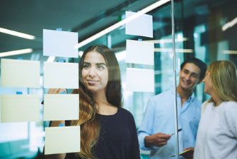 Campus group sticking postit notes on glass wall