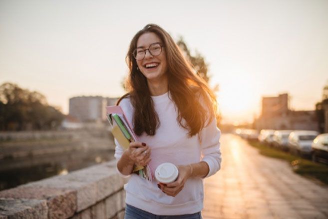 Female smiling holding books and coffee