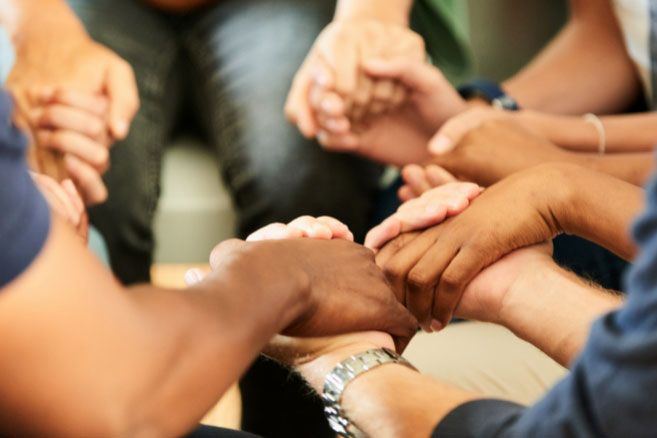 Group holding hands praying