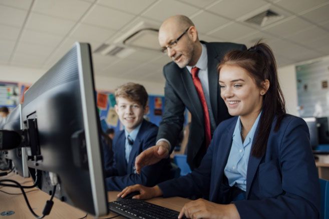 School students guided by teacher in computer room